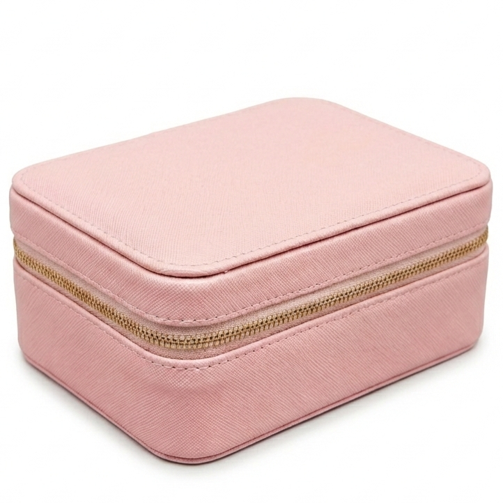 Lukket lyserødt smykkeskrin med guldlynlås set fra hjørnet på en hvid baggrund. Kompakt og stilrent design til smykkeopbevaring